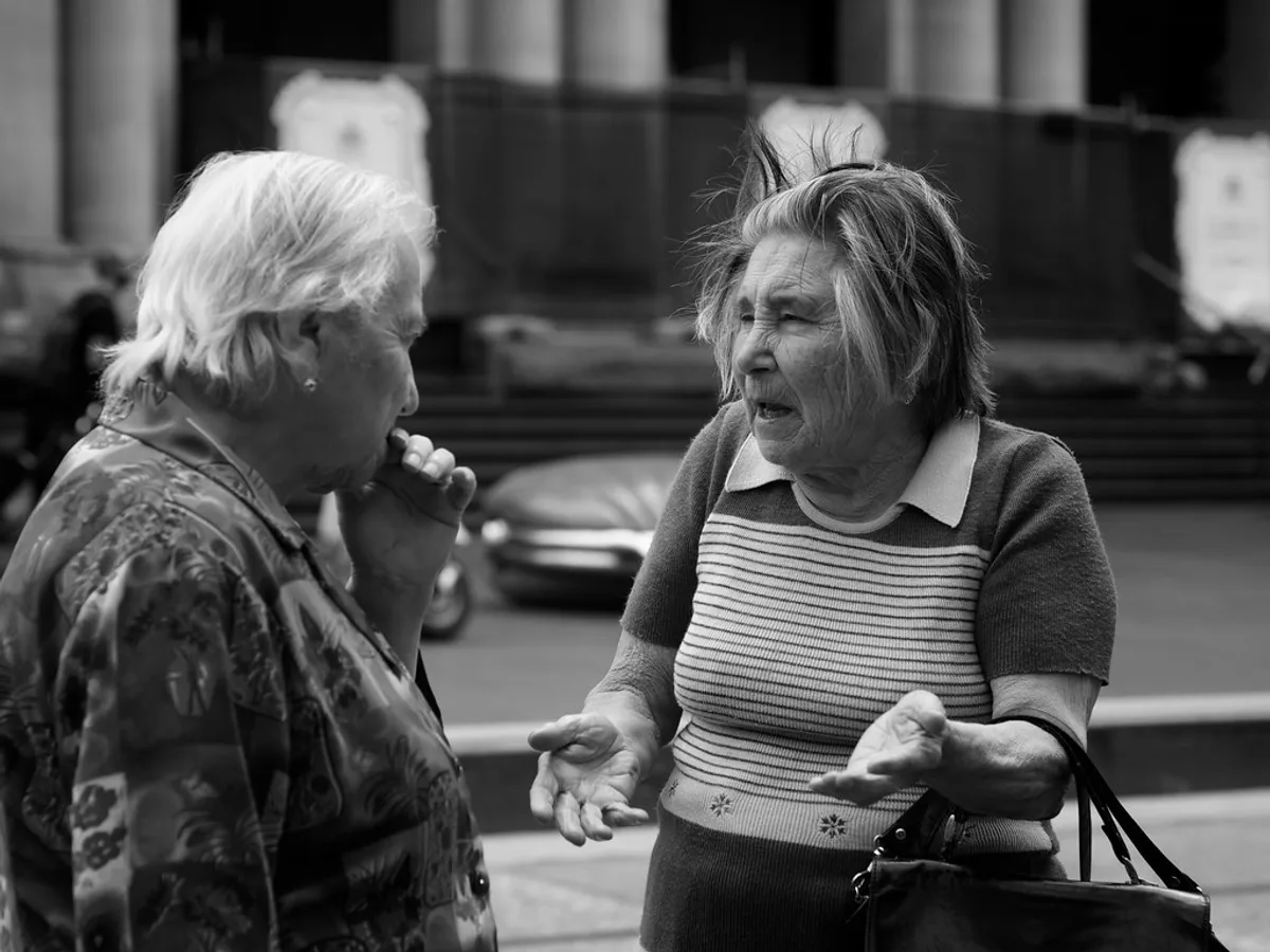 Two older friends in an animated street conversation